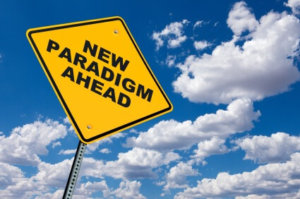 A yellow road sign with the words new paradigm ahead against a blue sky.