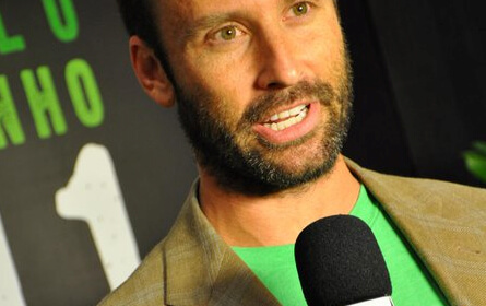 A man in a green shirt is holding a microphone.