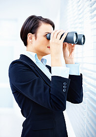 A business woman looking through binoculars.