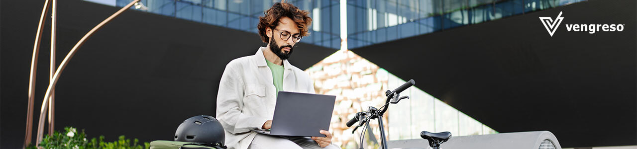 man with glasses in front of his laptop outside on his bike researching sales tools