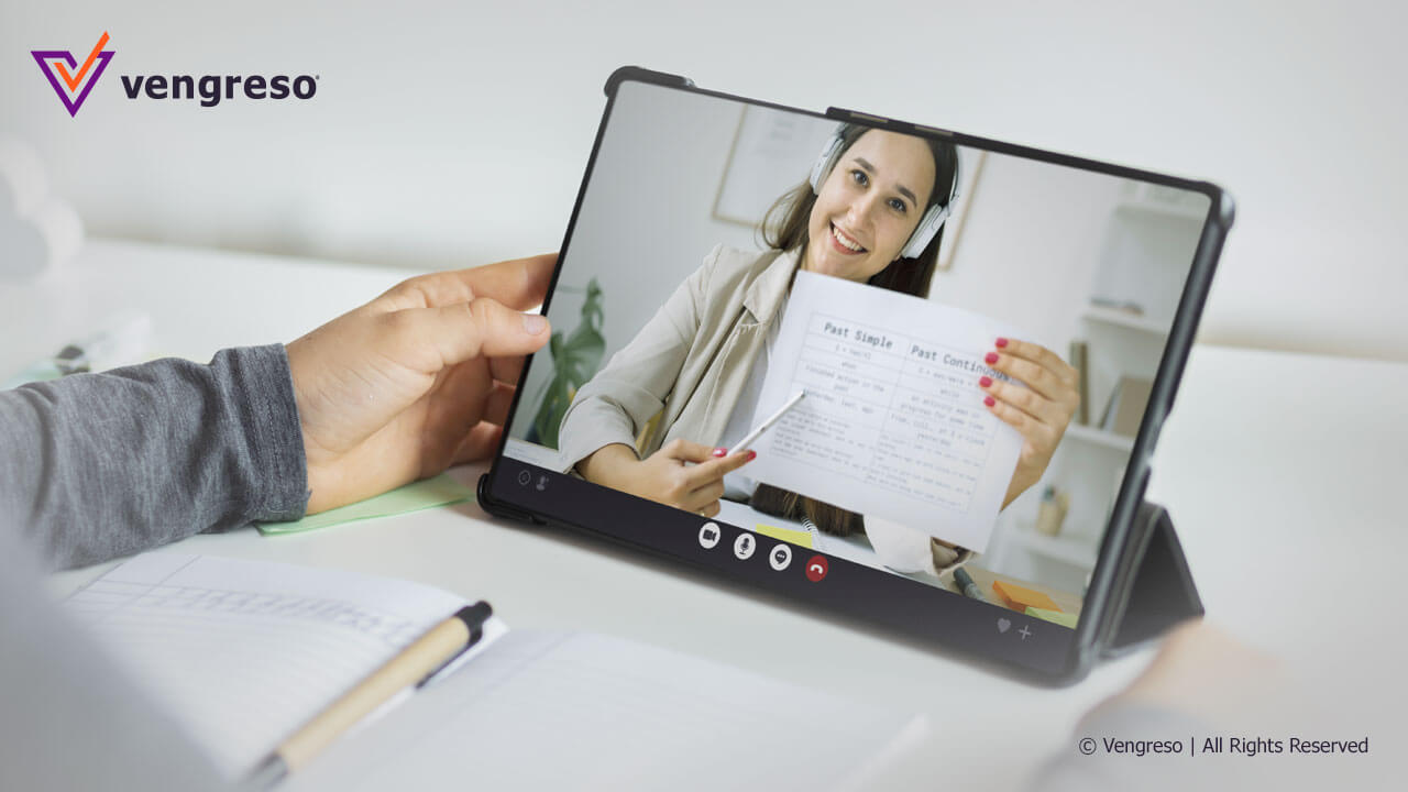 Hand holding a tablet with a person virtually teaching
