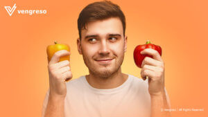 Guy holding a yellow pepper in one hand and a red pepper in the other