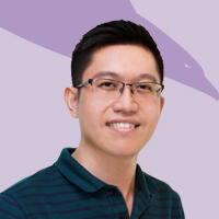 A man in glasses is smiling as part of our team in front of a purple background.