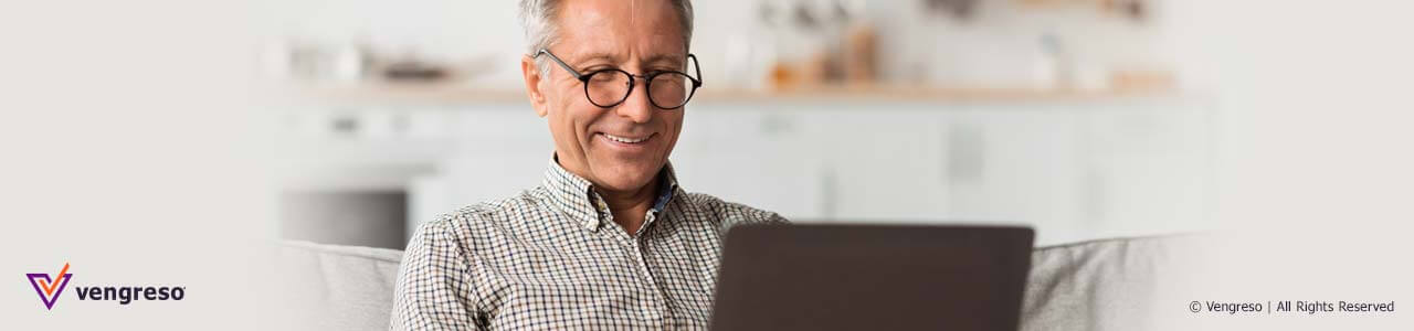 man with glasses smiling in front of computer