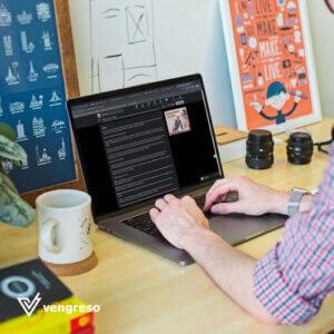 a close up of a woman's hands on a laptop on a desk next to a cup doing his LinkedIn profile optimization