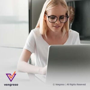 woman with glasses looking at computer