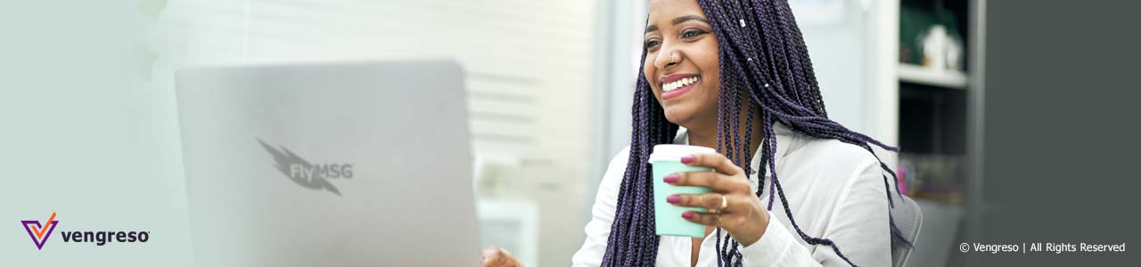woman holding cup smiling in front of computer