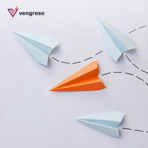 three white paper airplanes and an orange one