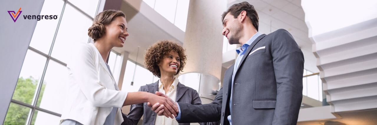 Two business people shaking hands in an office to initiate a LinkedIn introduction.