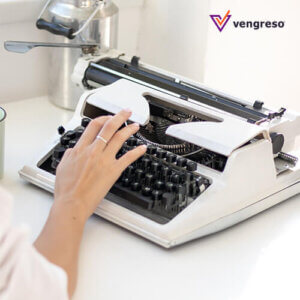A woman typing on a typewriter at a desk.